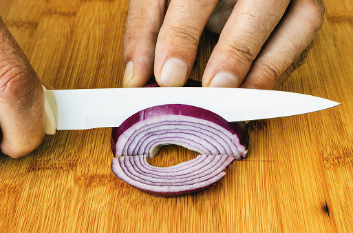 a man with a ceramic knife on a cutting board cuts an onion