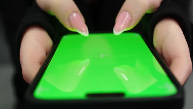 Female hands press on the phone screen. Green phone screen for product placement. Gestures on the touch screen.