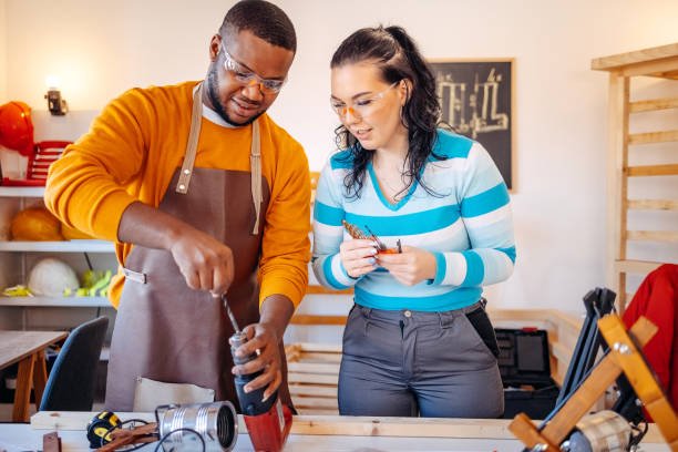 istock Couple starting new business working in carpenter workshop using electric drill 1932084437