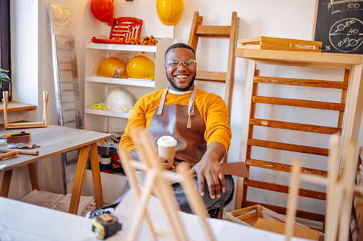 Young black man having a cup of coffee and relaxing after working as carpenter