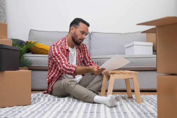 istock Man with instruction for installing furniture in apartment 1932098525