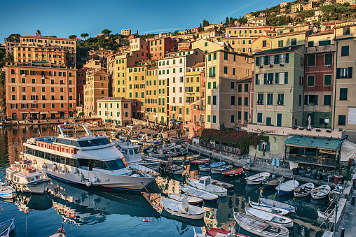 Scenic Mediterranean riviera coast. Sunset view of Camogli town in Liguria, Italy. Travel background with colorful houses and boats.