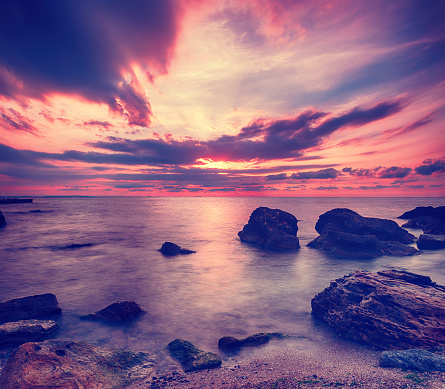 Beautiful colorful sunrise at the sea with dramatic clouds and boulders. Beauty world natural outdoors travel background
