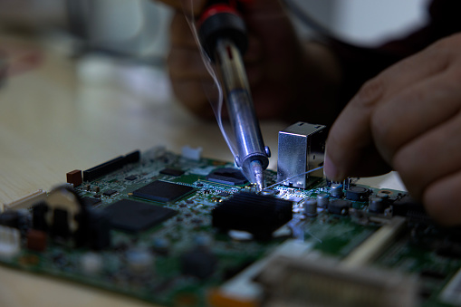 technician soldering a mother board circuit