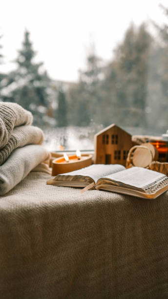 istock Cozy winter photo, stack of sweaters, open Bible, tea and candle 1932158167