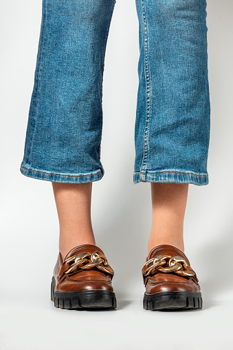 Close-up of female legs in jeans and brown casual leather shoes. Women's summer shoes