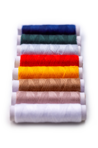 Colorful spools of thread, isolated on a white background. High angle view, studio shot.