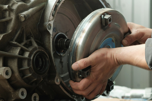 The torque converter is in the hands of an auto mechanic. Assembly of an automatic transmission. Installing the torque converter.
