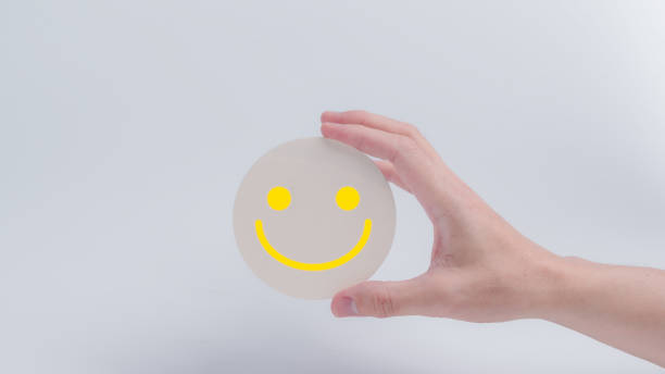 istock Customer service evaluation and satisfaction survey concepts. The client's hand holding  the happy face smile face icon on circle wood 1932201515