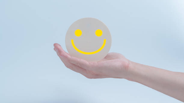 istock Customer service evaluation and satisfaction survey concepts. The client's hand holding  the happy face smile face icon on circle wood 1932202042