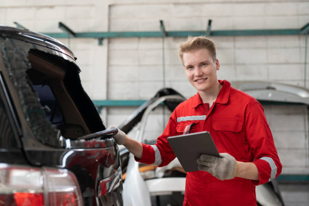 istock Car mechanic man in red uniform using tablet checking rear window broken of car at garage auto service. Car repair and maintenance concept. 1932254306