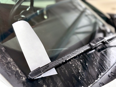 Parking fine ticket left on car dirty window after rain or snow. Place for text.