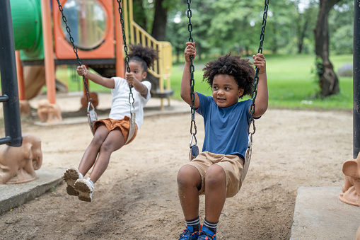 Happy African American little boy and girl have fun at the playground in the park