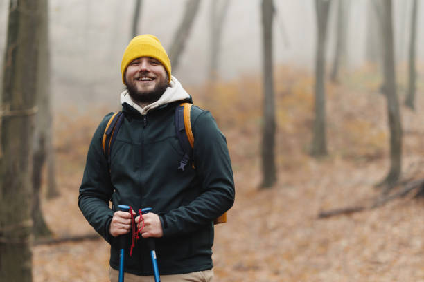 istock Confident young man doing walking on the mountains, he is using trekking poles and carrying a backpack, freedom and sports concept 1932296771