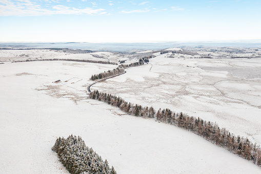 Aerial view of snowy fields with tree and road covered with ice in winter