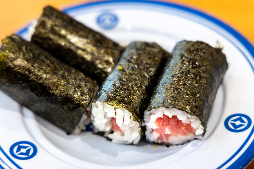 A set of four tuna sushi rolls on a white plate.