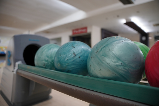 multi-colored bowling balls lie on shelf in bowling club