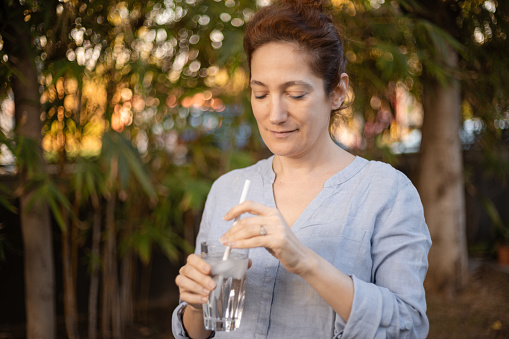 Caucasian woman using a straw to take a sip of ice cold water, part of a series for sensitive teeth