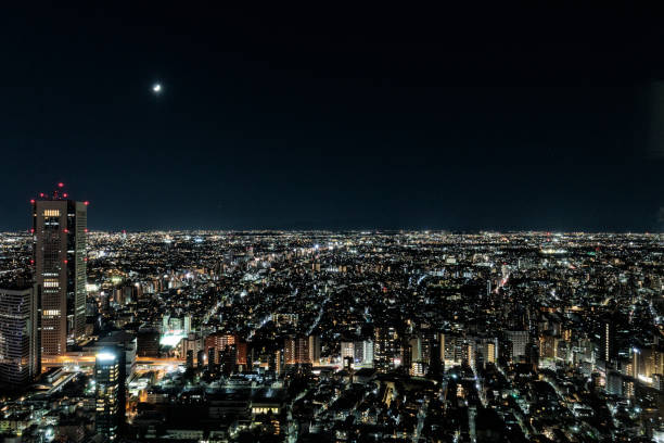 The moon floating in the clear sky and the cityscape beautifully illuminated by lights