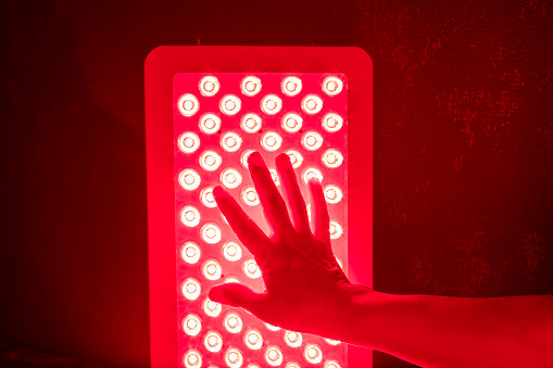 Closeup of hand touching Red Light Therapy Panel LEDs