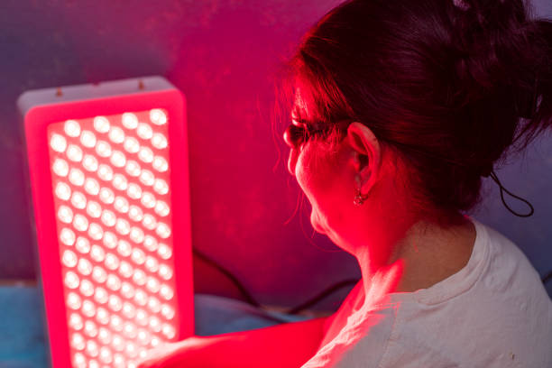 istock Senior Woman doing the Red Light Therapy Session with Panel at home 1932414101