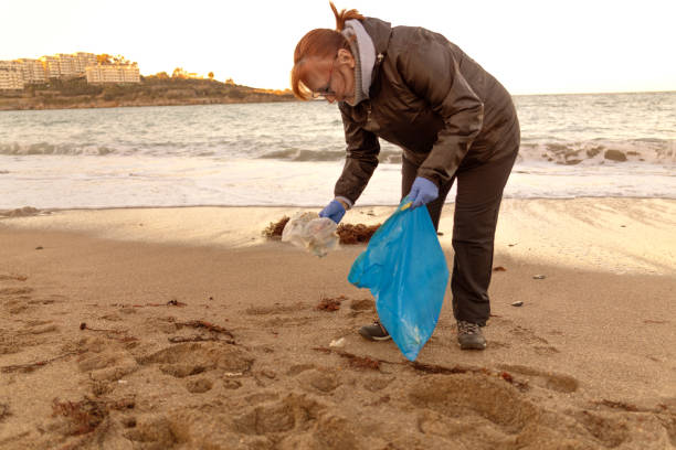 istock Volunteer mature woman keep clean on beach 1932415152
