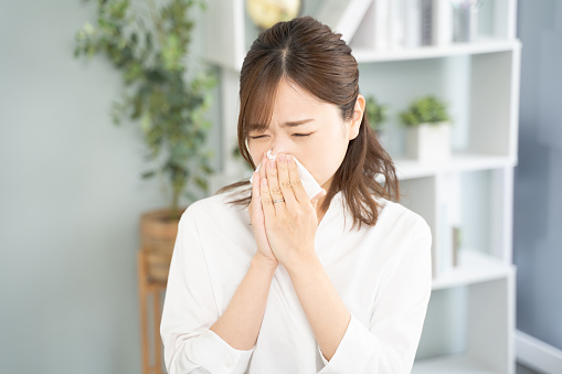 A woman blowing her nose because she is not feeling well.