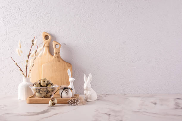 istock Kitchen stone countertop decorated for Easter in light colors. ceramic figurines of bunny, a vase with willow twigs, a bowl with quail eggs 1932474300