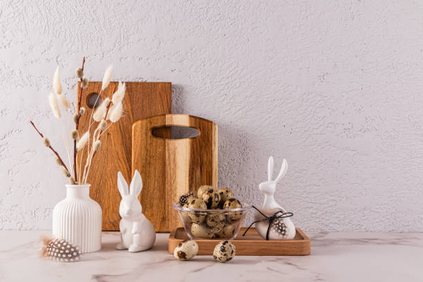istock Stylish eco-friendly background for Easter holiday with ceramic Easter rabbit figurines, vase with willow twigs, bowl with quail eggs. 1932474799