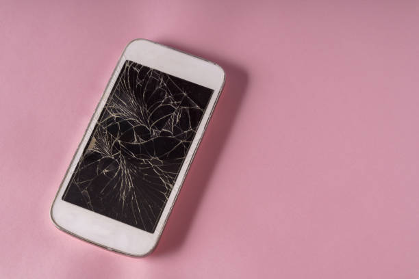 istock Broken mobile phone with cracked display over pink color background. 1932483946