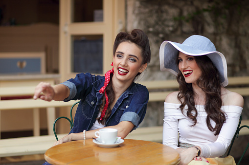 Two young women sitting at a table with drinks and having real fun.