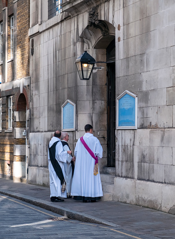 A convocation of clergymen waiting outside St Vedast alias Foster church in Foster Lane, London EC2. The original medieval church was badly damaged in the Great Fire of London in 1666 and was rebuilt in the late 17th century.