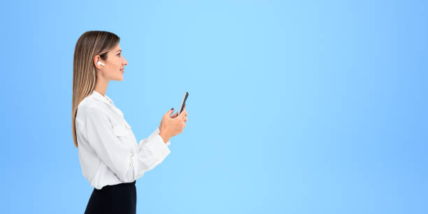 istock Smiling businesswoman typing in smartphone on empty copy space blue background 1932531386