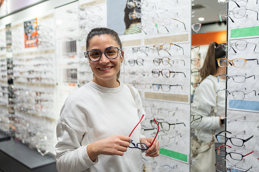 Woman Choosing Eyeglasses In Optical Store