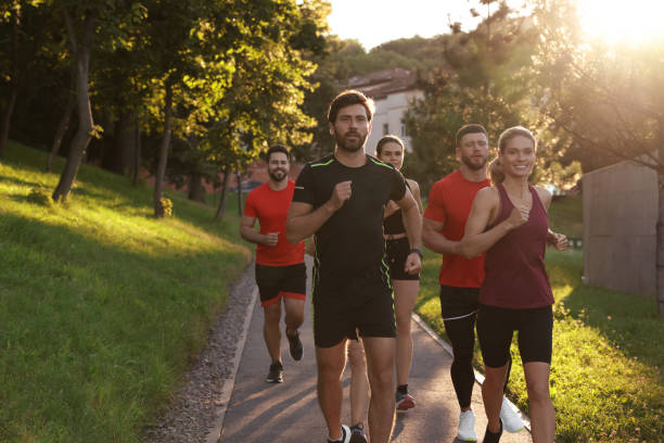 istock Group of people running outdoors on sunny day. Space for text 1932547074