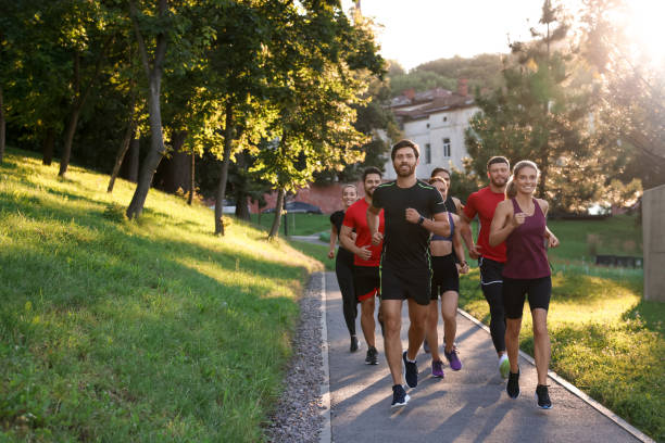 istock Group of people running outdoors on sunny day. Space for text 1932548703
