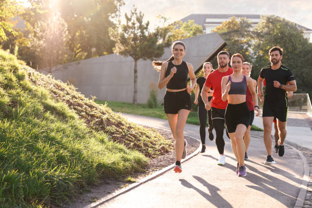 istock Group of people running outdoors on sunny day. Space for text 1932548743