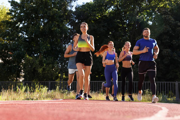 istock Group of people running at stadium on sunny day. Space for text 1932570175