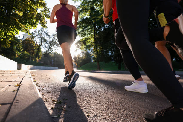 istock Group of people running outdoors on sunny day, back view 1932571262