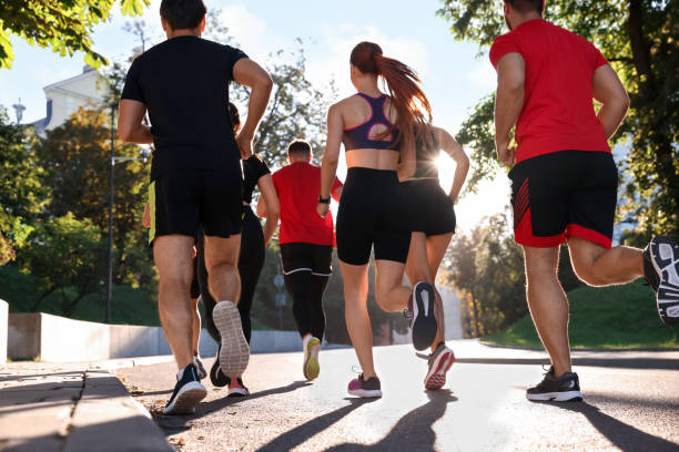 istock Group of people running outdoors on sunny day, back view 1932571265