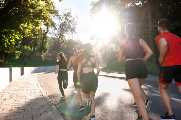 istock Group of people running outdoors on sunny day, back view 1932572307