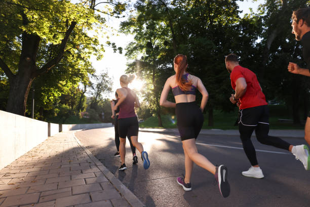 istock Group of people running outdoors on sunny day, back view 1932572878
