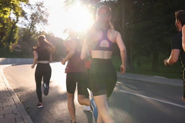 istock Group of people running outdoors on sunny day, back view 1932573396