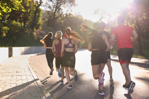 istock Group of people running outdoors on sunny day, back view 1932573945