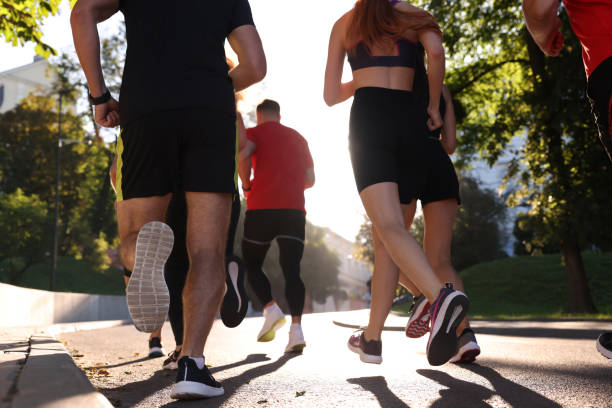 istock Group of people running outdoors on sunny day, back view 1932575035