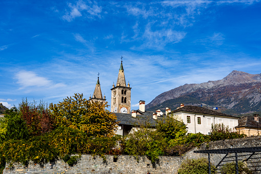 The two bell towers of the Cathedral of Santa Maria Assunta are the tallest structure in Aosta and in the entire Aosta Valley region. In the background the majestic Alps under an intensely blu sky.