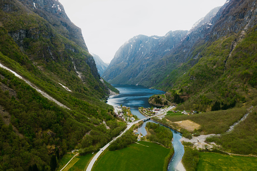 Drone high-angle photo of beautiful summer green mountain valley with cars on highway and the authentic Norwegian village in Nærøyfjord, Western Norway, Scandinavia