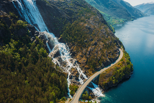 Drone high-angle photo of the curve road above the beautiful Langfoss waterfall with view of beautiful fjord  in South Norway
