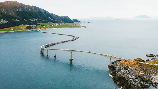 Drone high-angle panoramic photo of idyllic road above the sea between the small Norwegian towns on the island during summer in Scandinavia