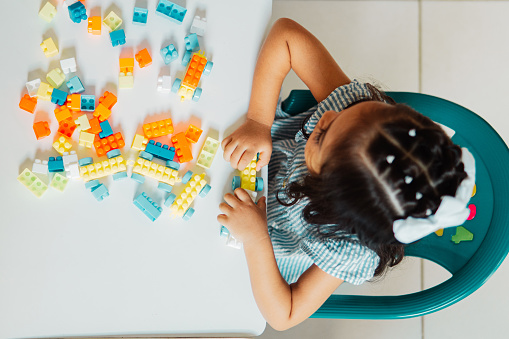 Cenital Hispanic little girl Preschool playing with colored blocks in a Kindergarten.